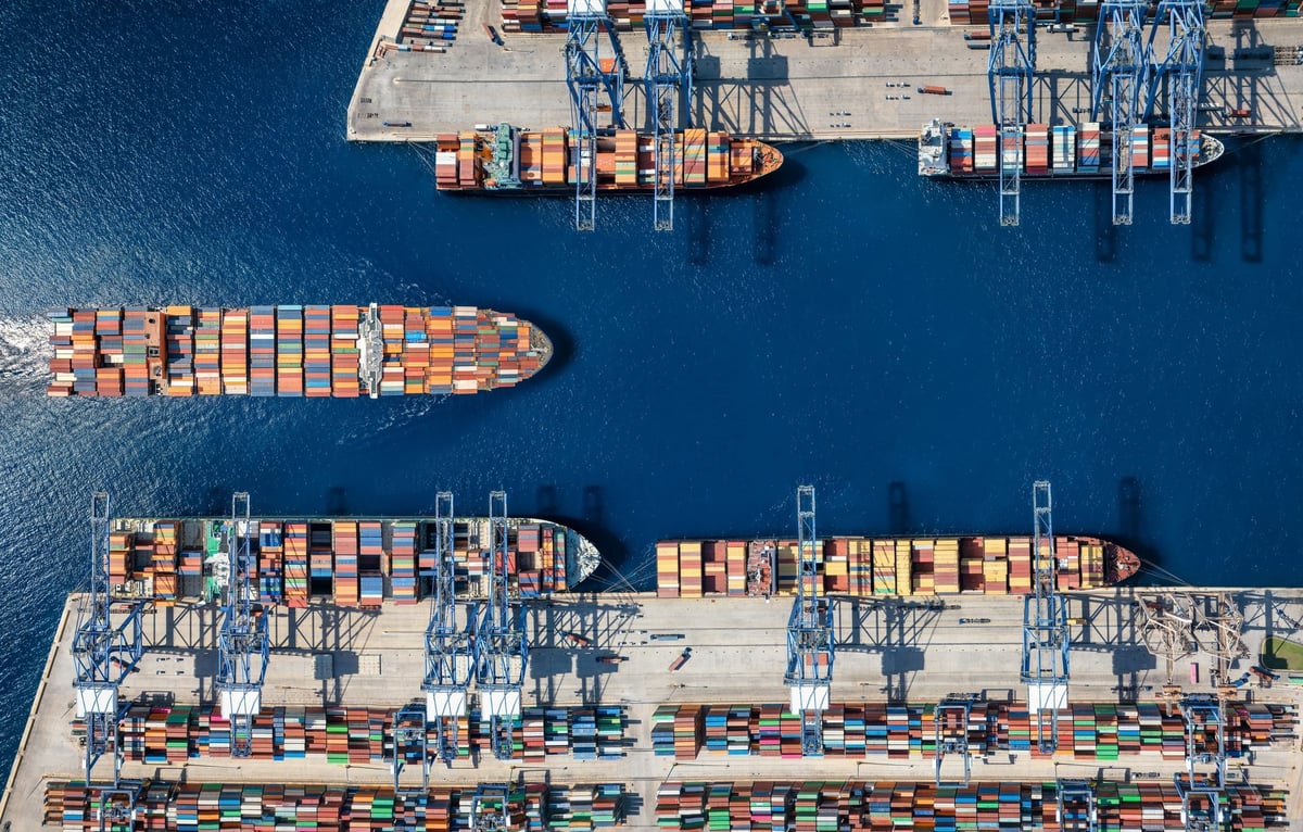 Aerial top down view of a large container cargo ship terminal harbor with loading activity and vessel traffic