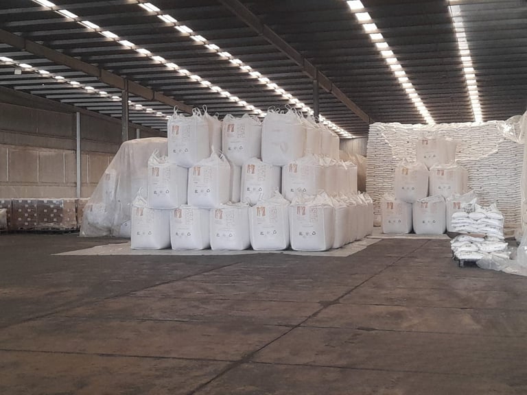 Large warehouse with stacked rolls of white plastic or foam material under industrial lighting