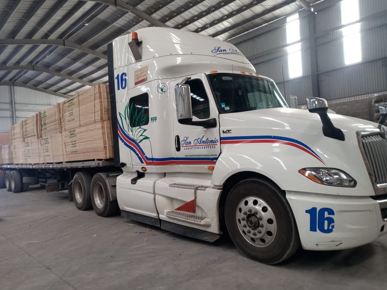 White semi-truck with number 16 and blue stripe parked in warehouse with cargo trailer